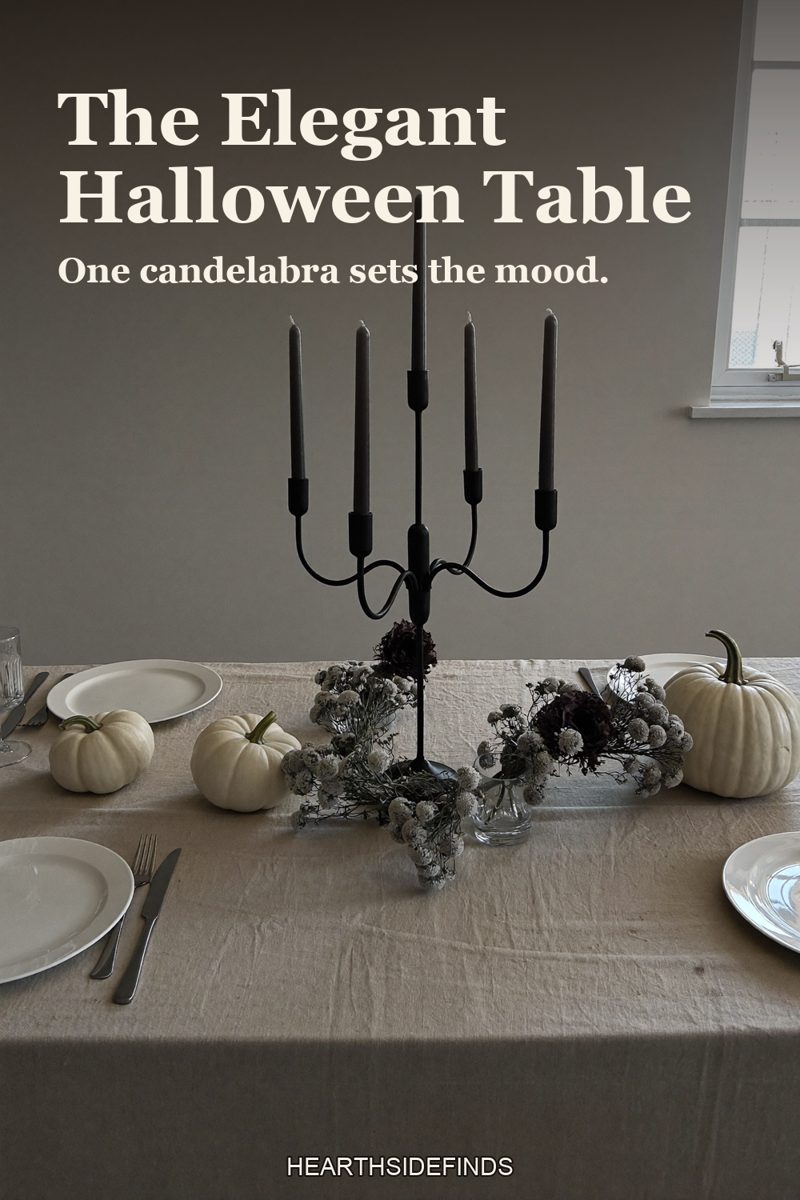 Linen-covered dining table with a black five-arm candelabra, black taper candles and white pumpkins.