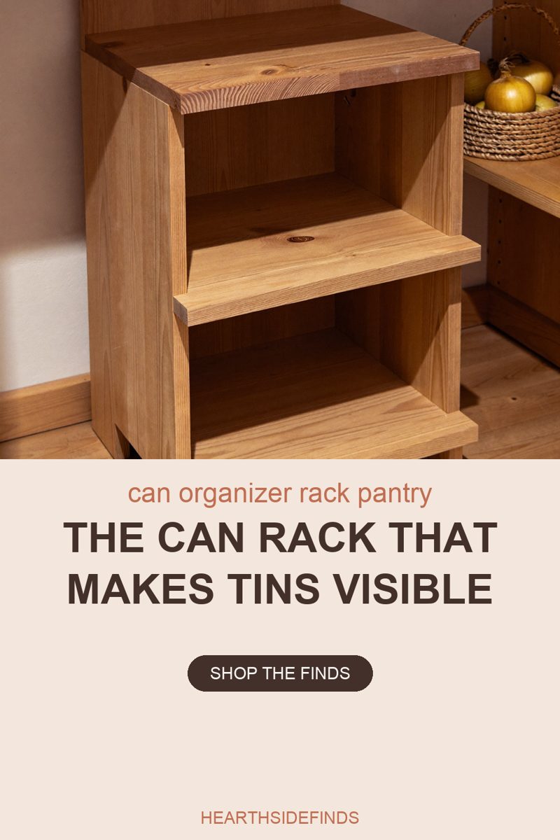 Photo of a pantry corner lit warmly from the left. A small two-bay organizer unit built from thick natural pine boards stands empty on the wooden pantry floor, its flat shelves stepped slightly, the grain and knots of the wood clearly visible. To its right on a shelf sits a round woven basket holding yellow onions, and pale plaster walls fill the background.